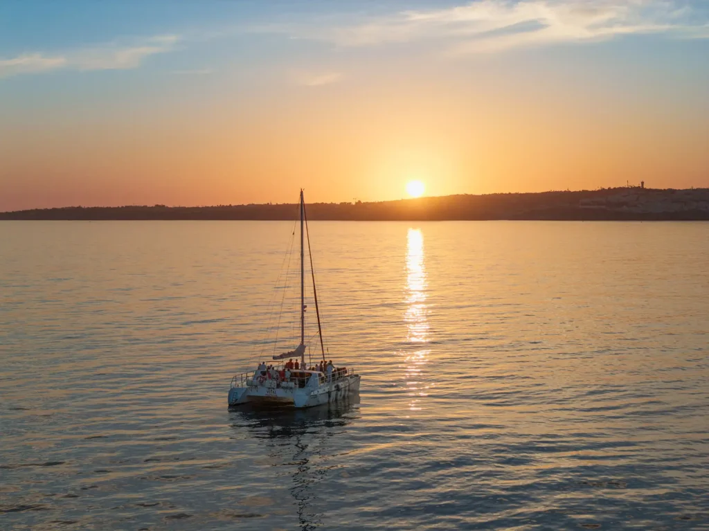 Sunset catamaran sailing off the Algarve coast, Portugal